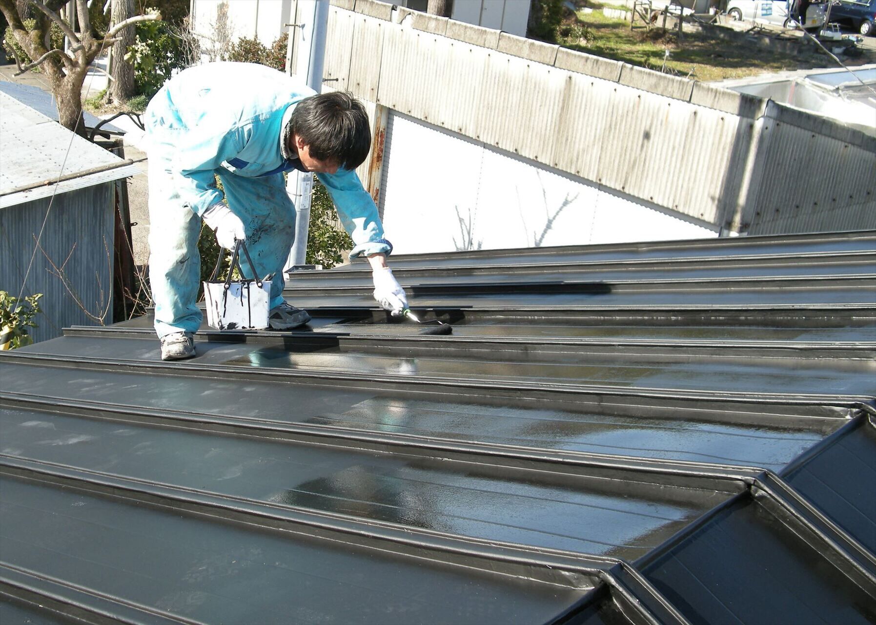 屋根の塗装作業を進める職人